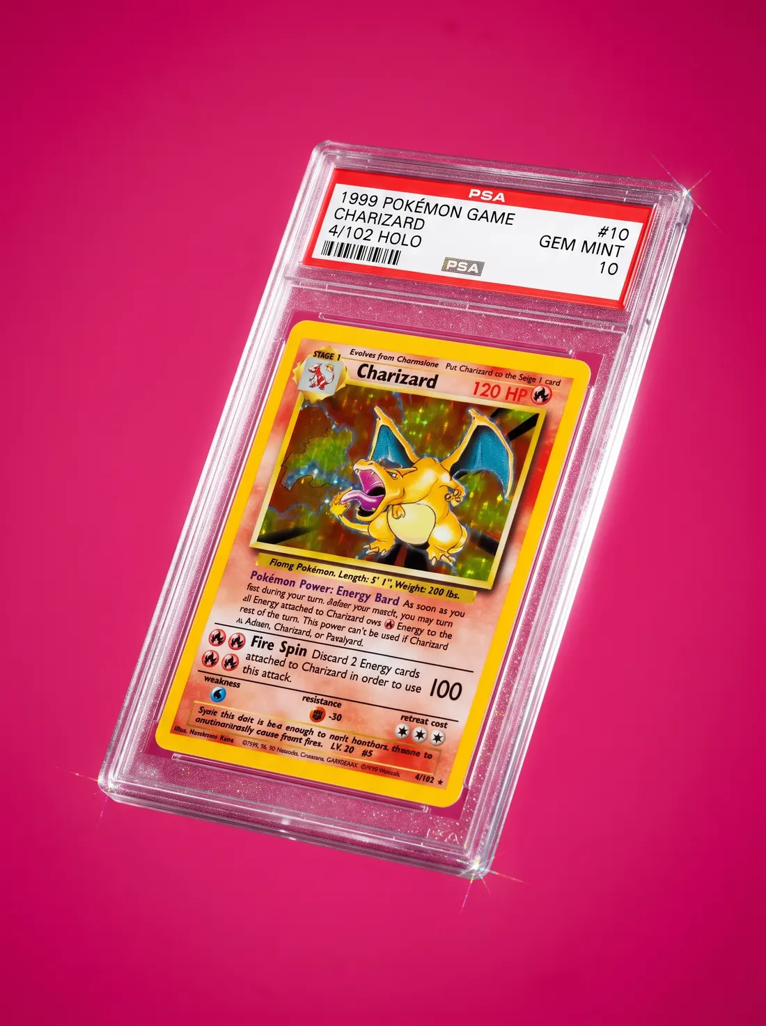 A PSA-graded holo card in its slab, lit on a magenta backdrop
